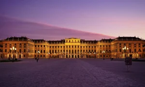 Schönbrunn-palasset i Wien badet i varmt kveldslys med lilla himmel i bakgrunnen.